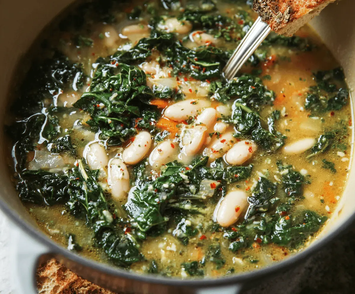 A steaming bowl of White Bean and Kale Soup garnished with fresh herbs, showcasing creamy beans and vibrant green kale in a hearty, healthy meal.