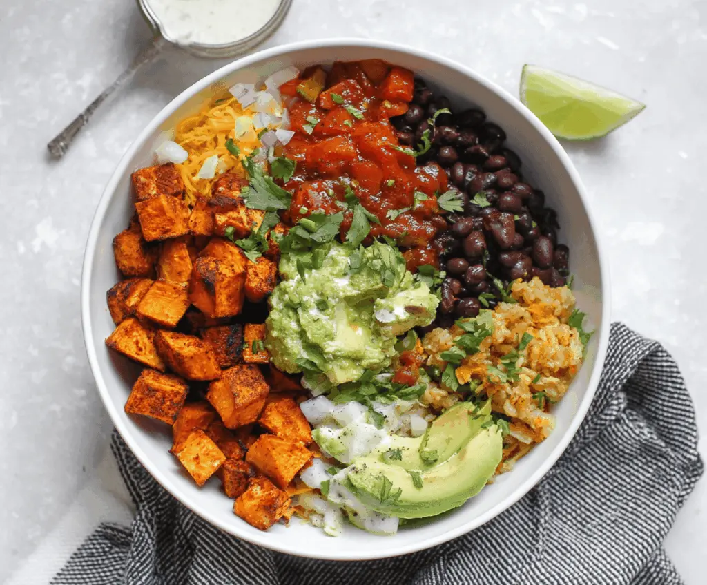Delicious chipotle sweet potato burrito bowl with fresh vegetables and spicy sauce.
