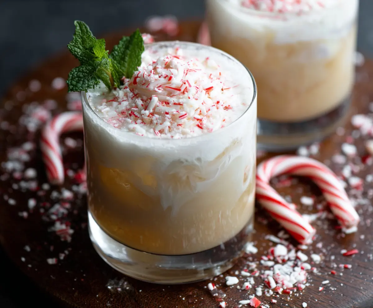 A delicious Peppermint White Russian cocktail in a clear glass garnished with peppermint and whipped cream.