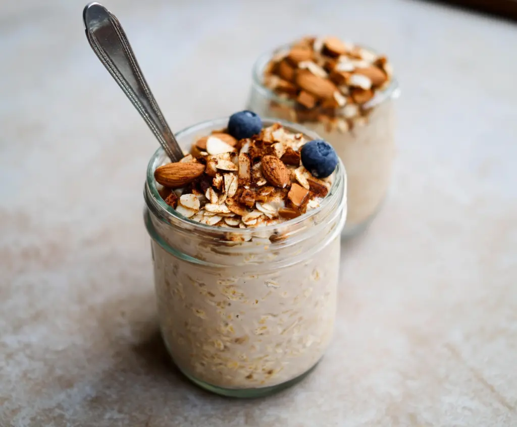 Creamy almond croissant overnight oats topped with sliced almonds and a drizzle of honey.
