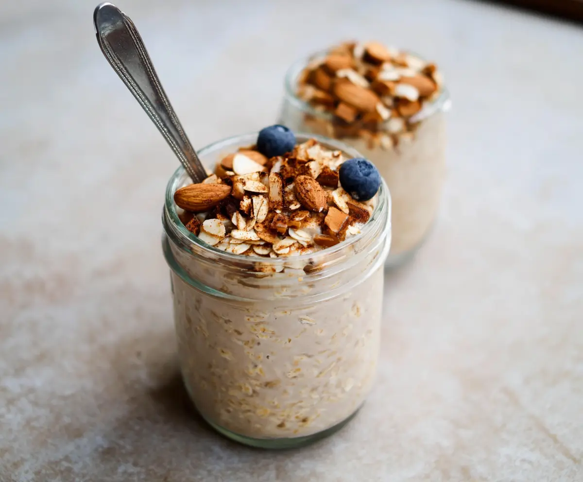Creamy almond croissant overnight oats topped with sliced almonds and a drizzle of honey.