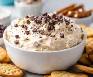 Creamy cookie dough dip served with chocolate chips and cookies, perfect for dessert or party snacks.