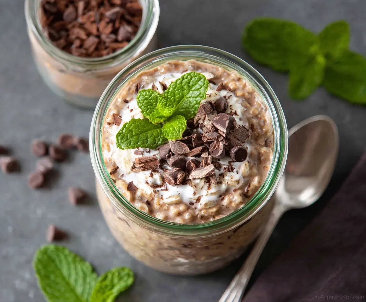 Delicious Mint Chocolate Chip Overnight Oats in a glass jar with fresh mint leaves.