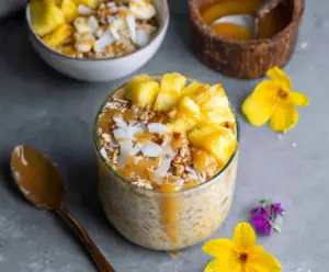 Creamy pineapple overnight oats in a glass jar topped with fresh pineapple pieces and chia seeds.