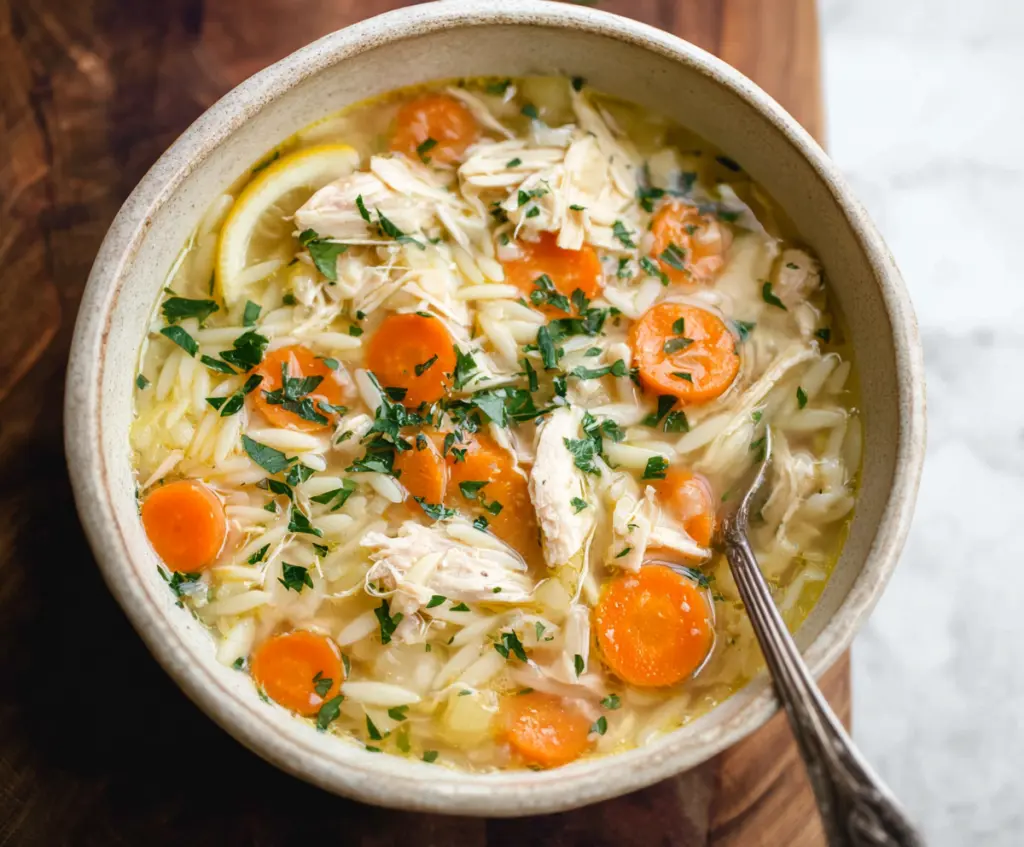 Delicious crockpot lemon chicken orzo soup in a bowl with fresh herbs