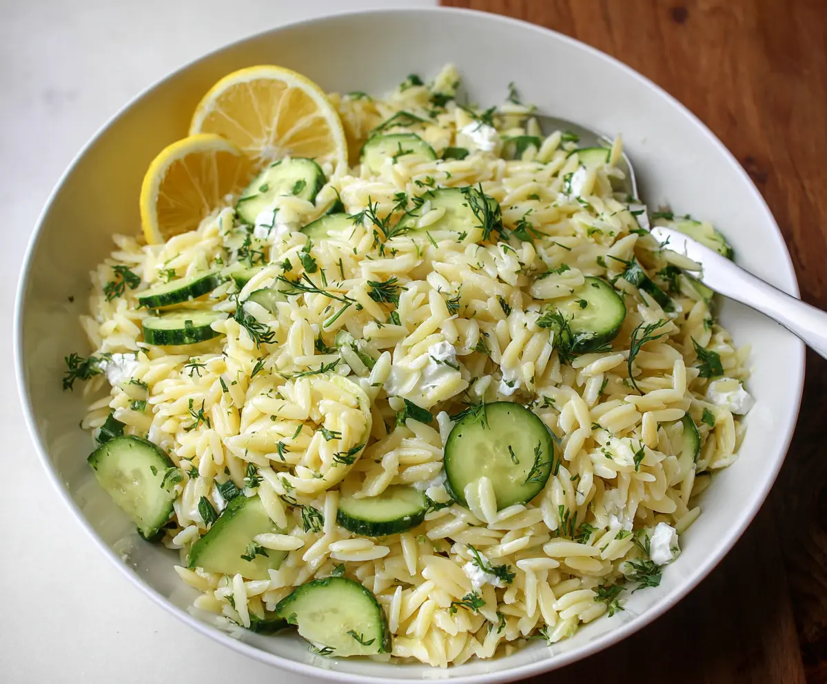 Fresh cucumber and lemon orzo salad in a white bowl, perfect for a healthy summer meal.