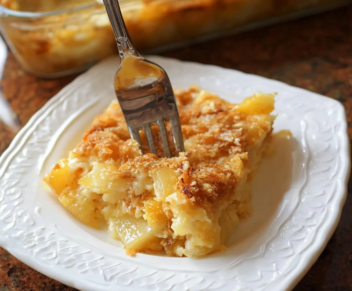 Delicious pineapple cheese casserole served in a baking dish, featuring golden melted cheese and sweet pineapple chunks.