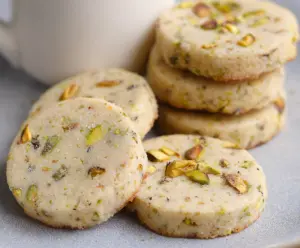 Delicious pistachio shortbread cookies on a white plate, showcasing their golden edges and nutty flavor.